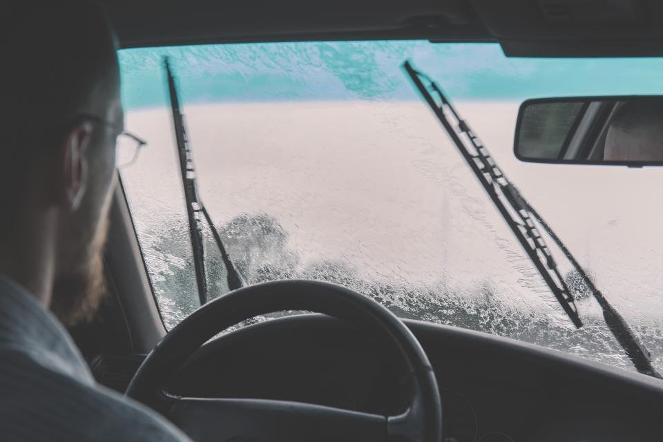 Conductor al volante de su vehículo con el parabrisas mojado por la lluvia