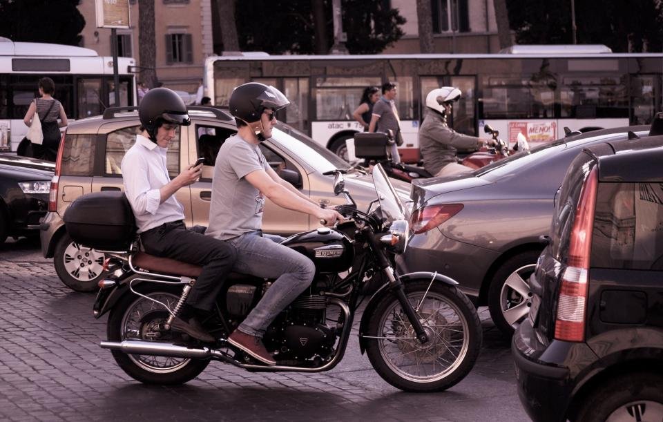 Motociclista con un pasajero avanzando entre el tráfico de la ciudad